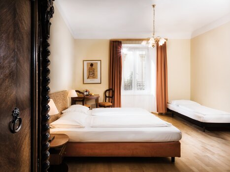 A bright triple room featuring two beds and a seating area. | © Hotel Mariahilf