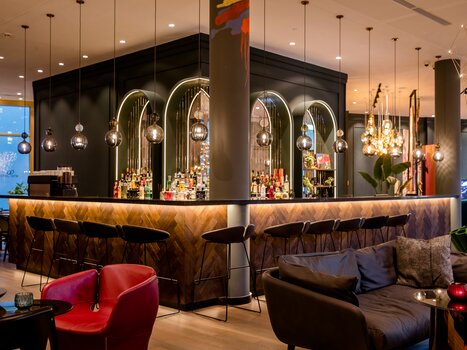 Elegant bar with stylish design and illuminated shelves. | © Motel One Austria GmbH