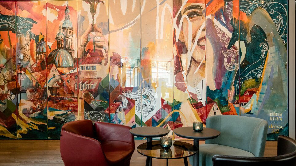 Bunte Wandmalerei mit Stadtansicht von Graz und stilisierten Figuren. | © Motel One Austria GmbH