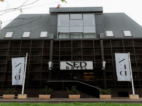 The NED Hotel in Graz featuring mirrored glass facade and hotel signage. | © NED Hotel