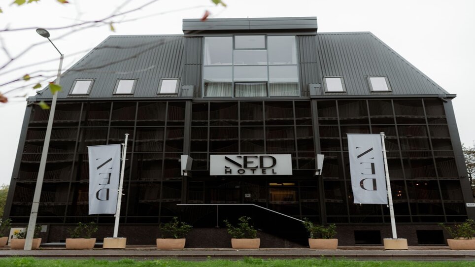L'hotel NED a Graz con facciata in vetro specchiato e cartello dell'hotel. | © NED Hotel