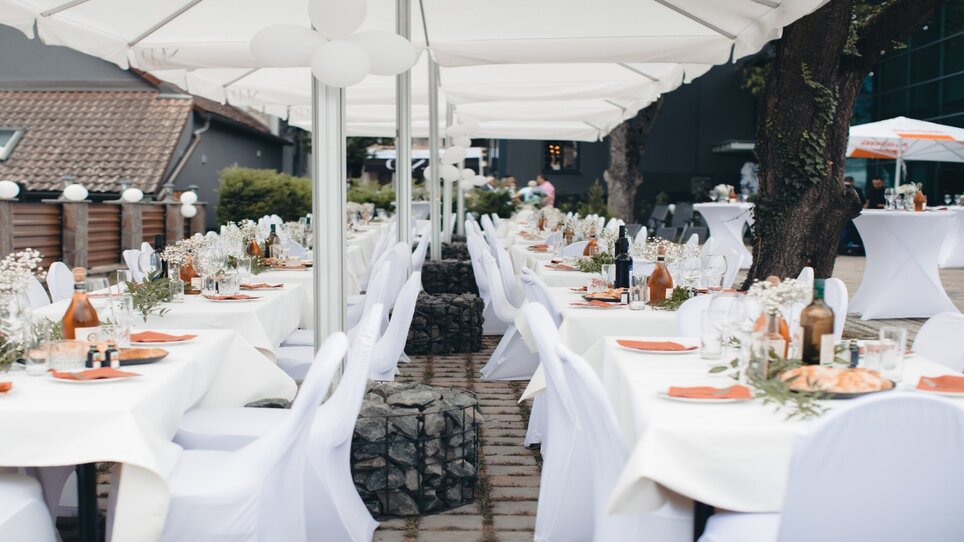 Tavoli apparecchiati all'aperto decorati con fiori e stoviglie. | © NED Hotel