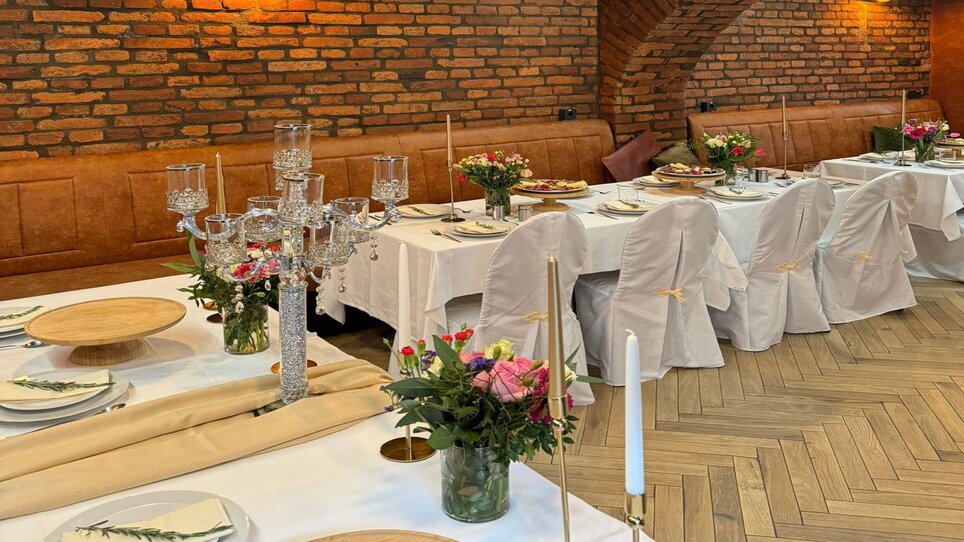 Tavoli decorati festosamente con fiori e candele. | © NED Hotel