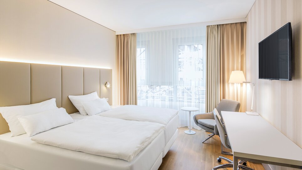 Modernes Zweibettzimmer mit zwei Betten und Schreibtisch. | © NH Hotel