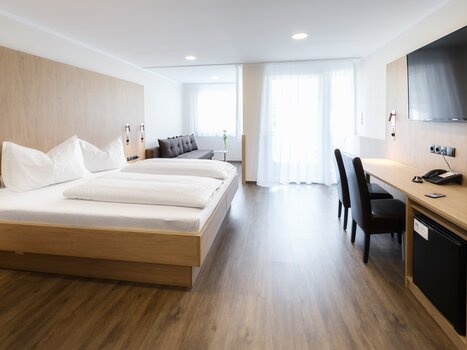 Bright double room with wooden furnishings and sofa. | © Ulrike Rauch