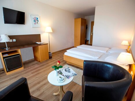 Bright room with double bed, table, and TV. | © Ulrike Rauch