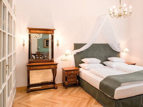 Stanza luminosa con letto matrimoniale e arredi eleganti. | © Robert Illemann