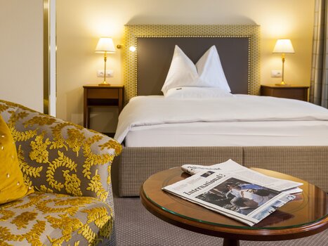 Cozy double room with bed and newspaper | © Parkhotel Graz