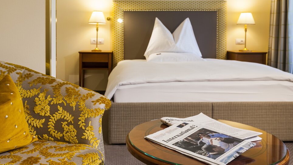 Cozy double room with bed and newspaper | © Parkhotel Graz