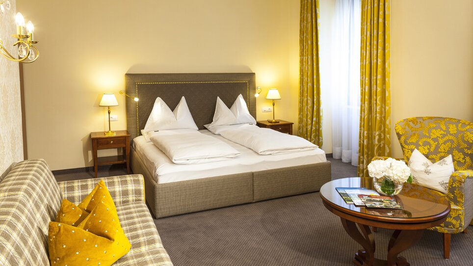 Double room with large bed and cozy seating area. | © Parkhotel Graz