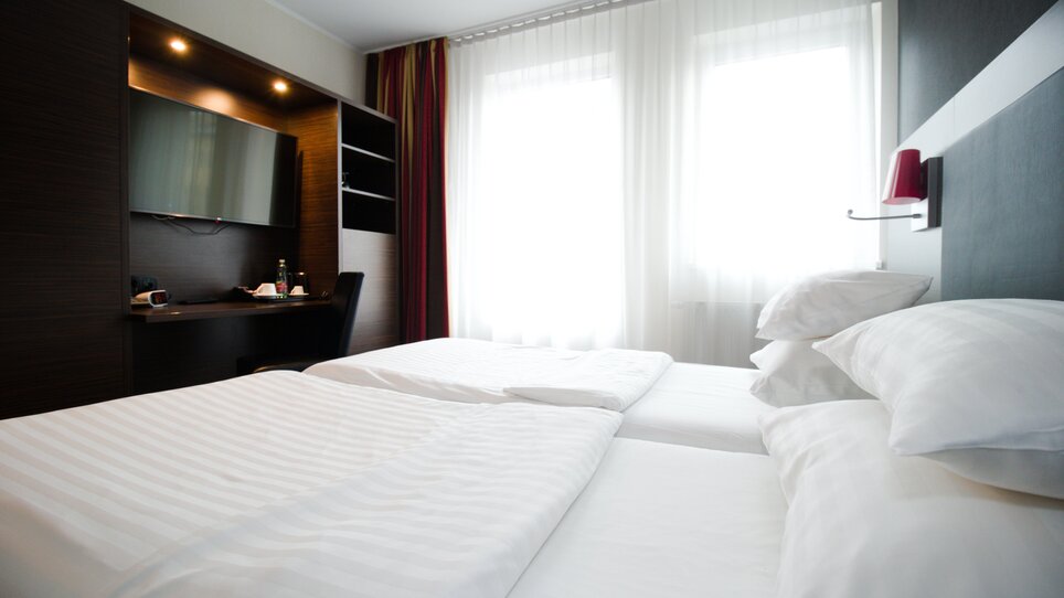 View of a double room with two beds and a desk. | © PLAZA INN Graz City