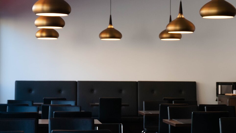 An interior space with elegant hanging lamps and black chairs. | © PLAZA INN Graz City