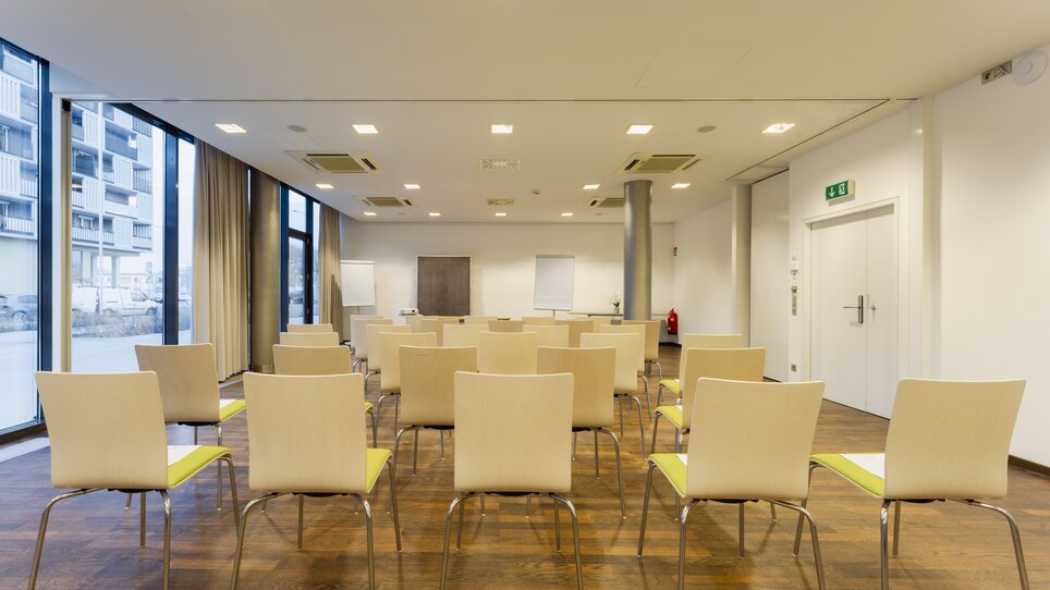 Empty conference room with rows of chairs and windows. | © Plaza INN Graz