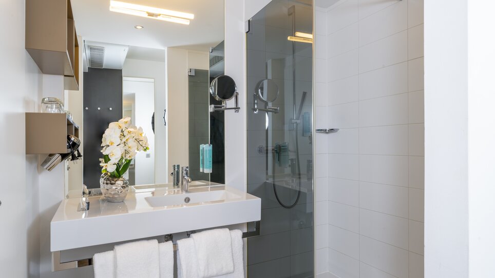 Bright bathroom with shower, sink, and towels. | © Plaza INN Graz