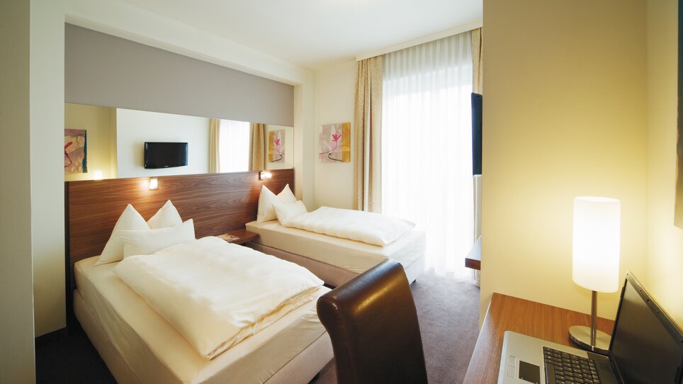 Bright double room with two beds and desk. | © Roemerstube