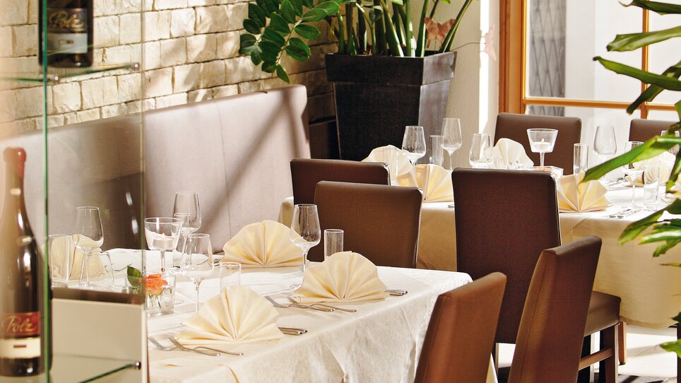 Elegant restaurant with plants and table settings. | © Roemerstube
