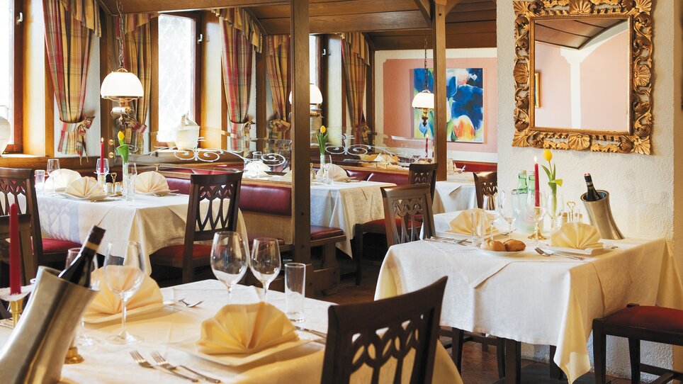 Rustic restaurant with table settings and double-arm chandeliers. | © Roemerstube