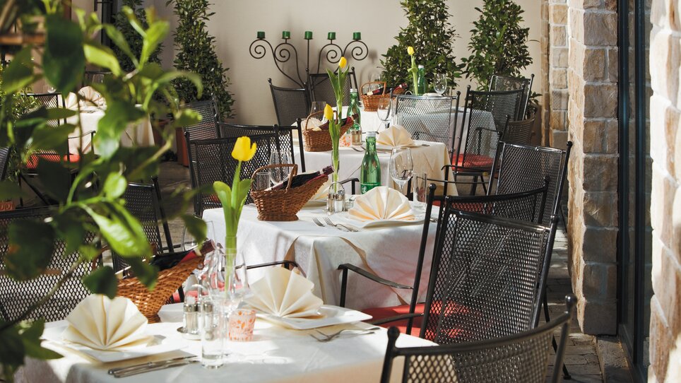 Tables and chairs in a cozy restaurant with plants. | © Roemerstube 