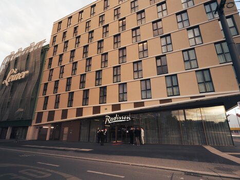 Außenansicht des Radisson Hotels mit Gästen am Eingang. | © Fabian Hasler