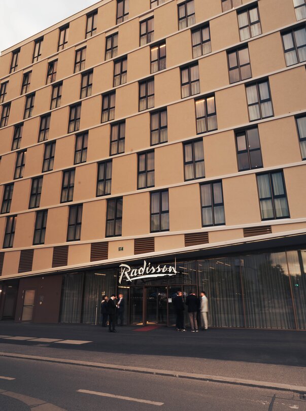 Außenansicht des Radisson Hotels mit Gästen am Eingang. | © Fabian Hasler