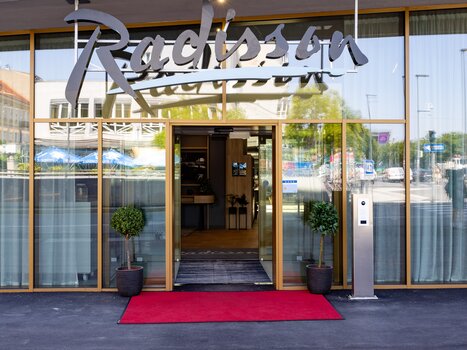 Entrance of the Radisson Hotel with red carpet and plants. | © Graz Tourismus - Harry Schiffer