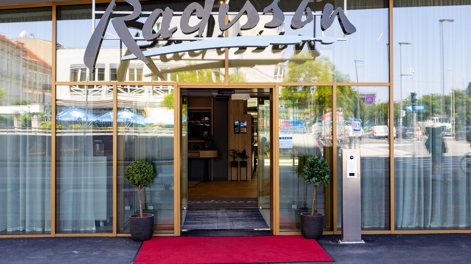 Entrance of the Radisson Hotel with red carpet and plants. | © Graz Tourismus - Harry Schiffer