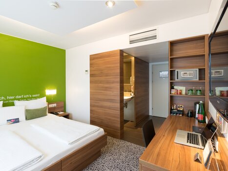 Bright double room with large bed, desk, and bathroom. | © Hotel Süd Art