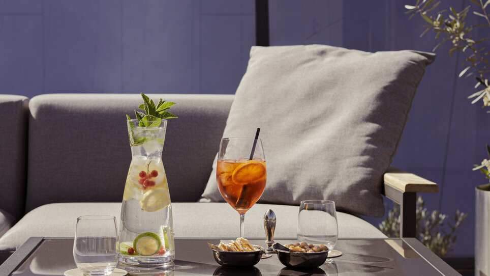 Carafe with beverage, cocktails, and snacks on a table. | © Schlossberghotel