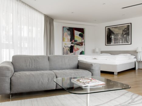 Modern double room with sofa, table, and floor-to-ceiling windows. | © Schlossberghotel