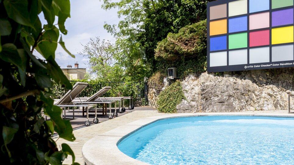 Pool area of Schlossberghotel Graz with loungers and color board. | © Schlossberghotel