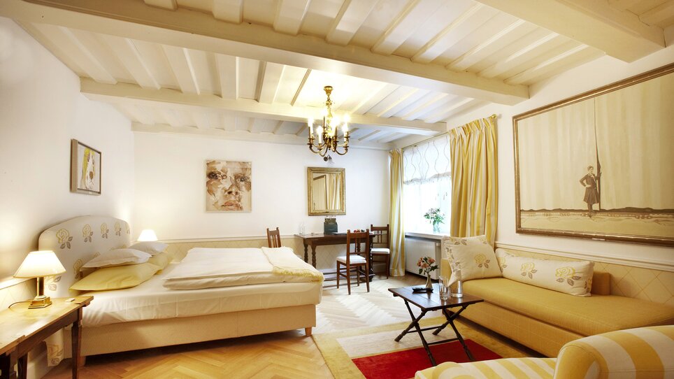 Bright room with large bed and artworks on the wall. | © Schlossberghotel