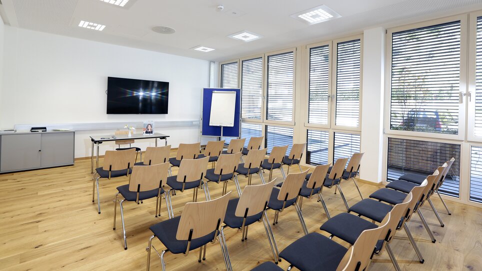 A meeting room with chairs, a screen, and windows. | © Foto Pachernegg