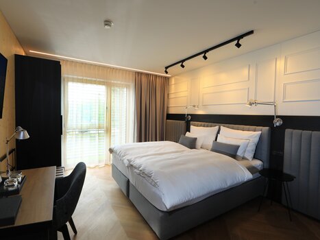 A bright bedroom with a double bed and workspace. | © Hotel Steiermarkhof
