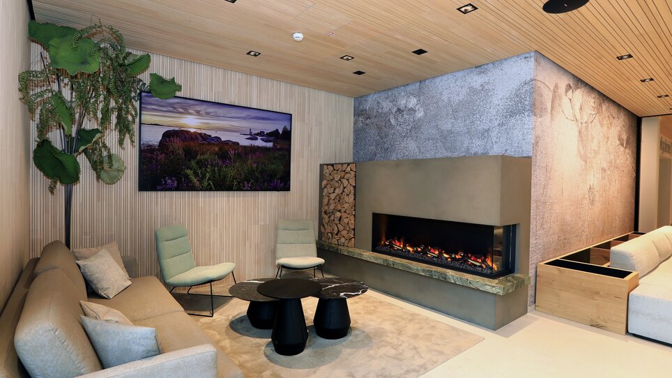 Lounge luminosa con divano, piante e camino moderno. | © Hotel Steiermarkhof