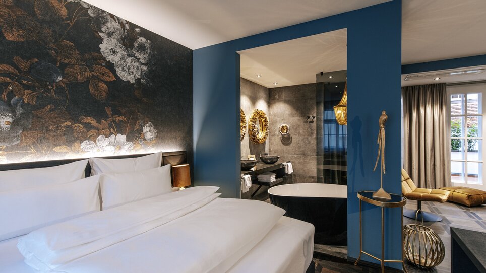 Stylisches Zimmer mit floralem Design und moderner Badewanne. | © Aiola Living