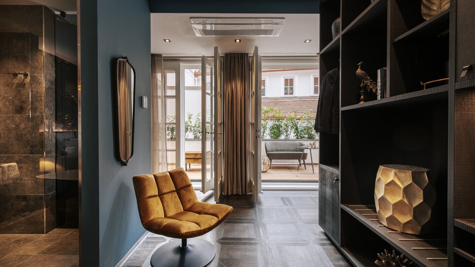 Ein stilvoller Flur mit einem orangefarbenen Sessel und Balkon. | © Aiola Living