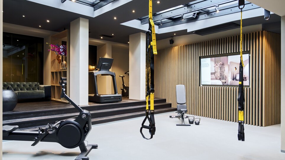 Fitnessraum mit TRX-Bändern, Laufband und Rudergerät im Aiola Living. | © Aiola Living