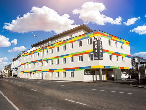 Luminoso edificio alberghiero con strisce colorate e finestre. | © sHome Hotel