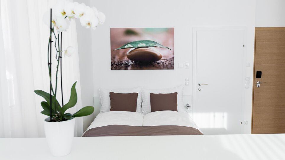 Camera doppia luminosa con grande letto e orchidea. | © sHome Hotel