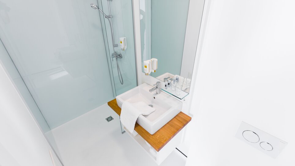 Bagno luminoso con doccia e lavandino. | © sHome Hotel