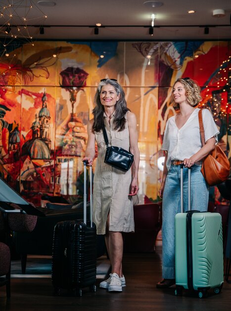 Two women with suitcases in a hotel lobby in Graz. | © Graz Tourismus - Mias Photoart